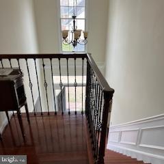 staircase with an inviting chandelier, wainscoting, and a decorative wall