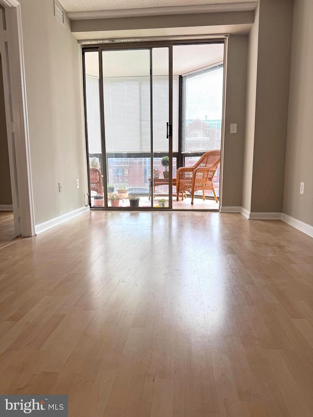 empty room with visible vents, baseboards, and wood finished floors