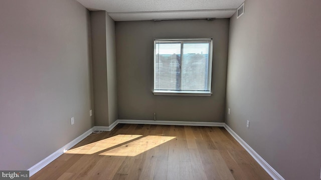 unfurnished room with visible vents, baseboards, and wood finished floors