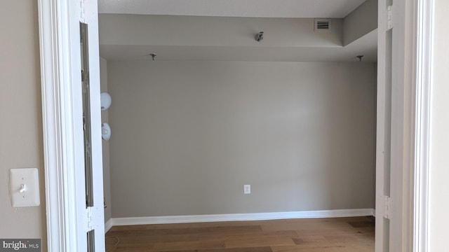 empty room featuring wood finished floors, visible vents, and baseboards