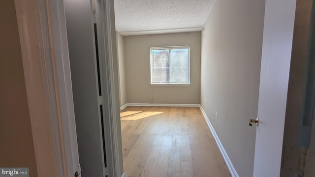 interior space with baseboards, a textured ceiling, and light wood finished floors