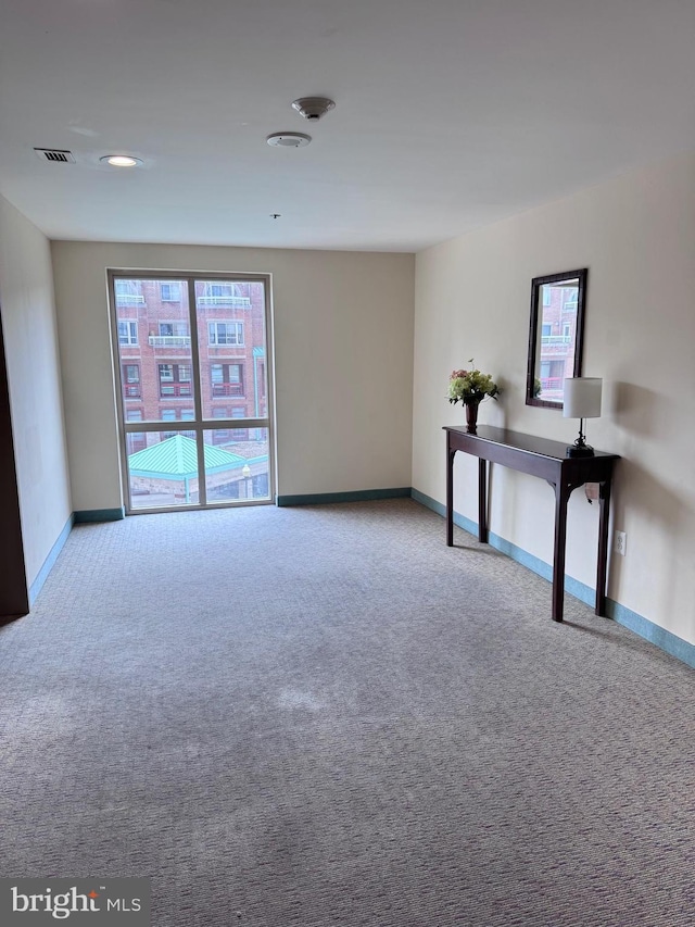 carpeted spare room featuring visible vents and baseboards