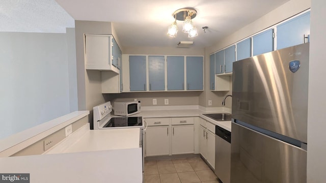 kitchen with light tile patterned floors, a sink, stainless steel appliances, light countertops, and blue cabinets