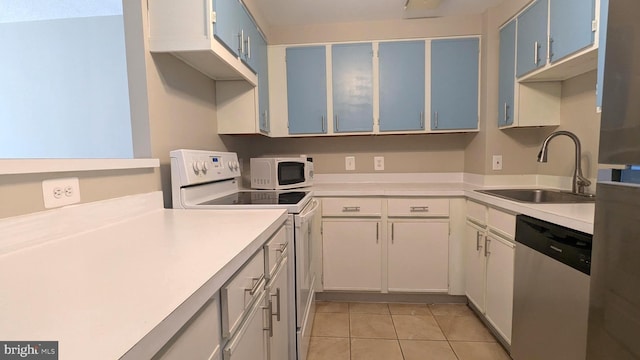 kitchen featuring white appliances, blue cabinetry, light tile patterned flooring, a sink, and light countertops