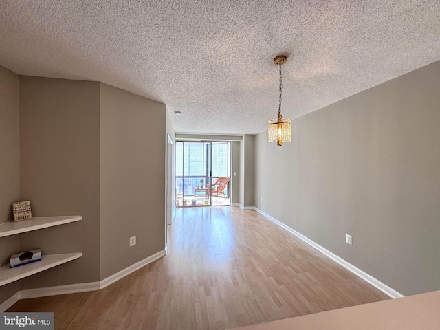 unfurnished dining area with a chandelier, baseboards, and wood finished floors