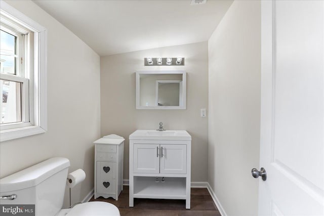 bathroom featuring baseboards, toilet, vaulted ceiling, wood finished floors, and vanity