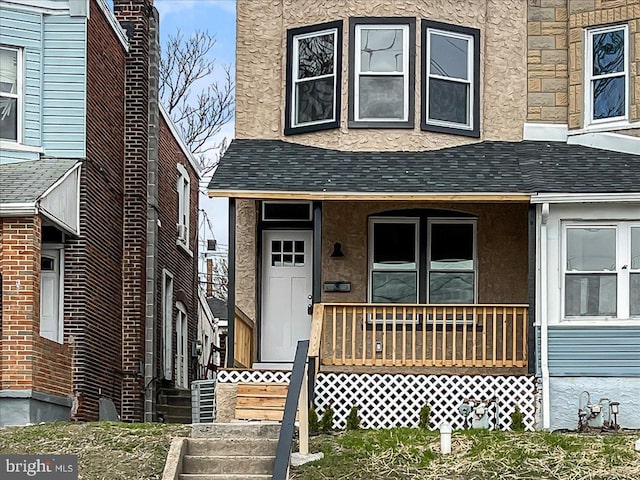 property entrance featuring covered porch, a shingled roof, and stucco siding