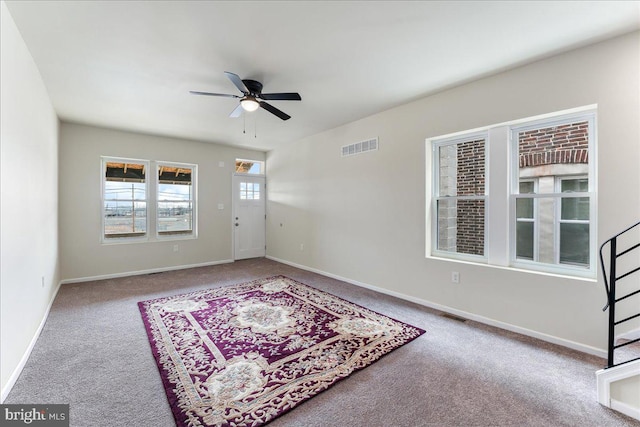 carpeted empty room featuring baseboards, visible vents, and ceiling fan