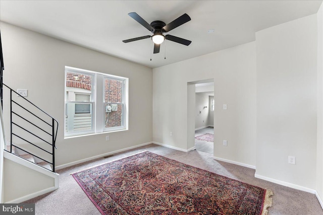 interior space with baseboards, stairs, and ceiling fan