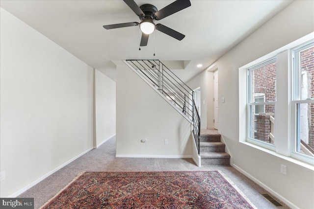 staircase featuring a ceiling fan, visible vents, carpet, and baseboards