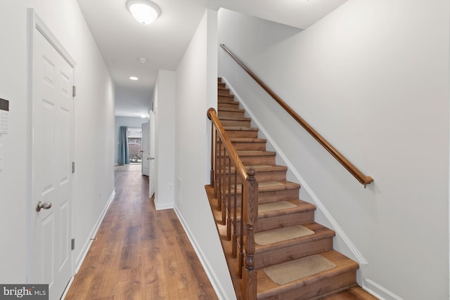 stairway with recessed lighting, wood finished floors, and baseboards
