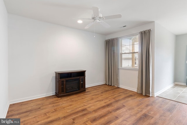 spare room with a ceiling fan, visible vents, baseboards, and light wood-type flooring