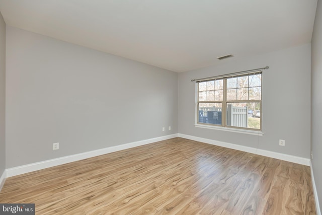 spare room featuring visible vents, baseboards, and wood finished floors