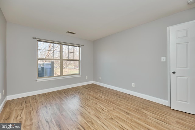 empty room featuring visible vents, light wood-style flooring, and baseboards