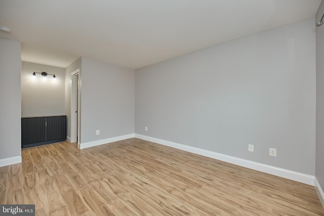 spare room featuring baseboards and light wood-style flooring