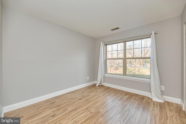 spare room with light wood-style floors, baseboards, and visible vents