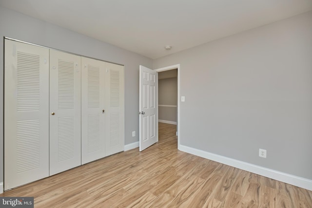 unfurnished bedroom with a closet, baseboards, and wood finished floors