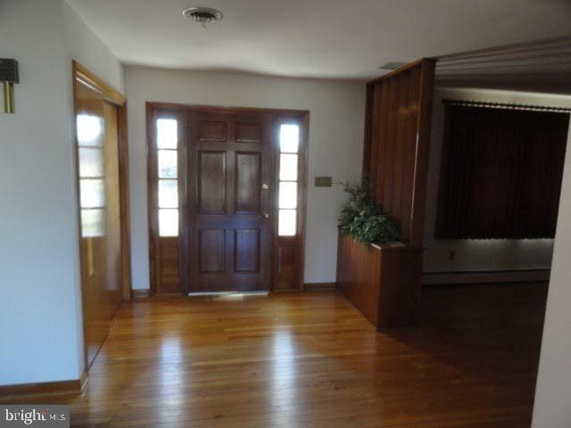 foyer entrance with visible vents, baseboards, and wood finished floors