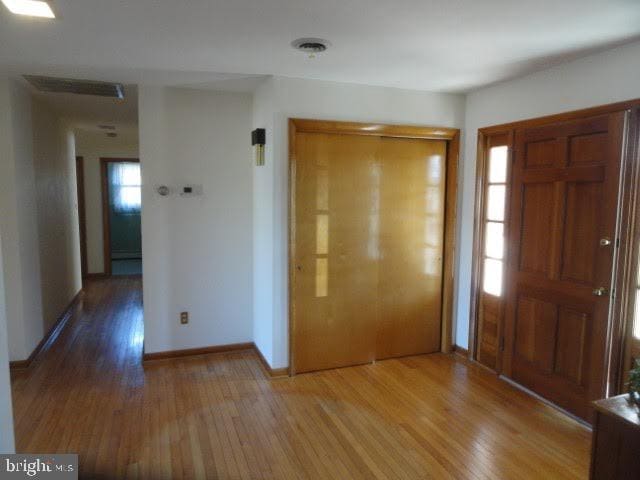 entrance foyer with visible vents, baseboards, and wood finished floors