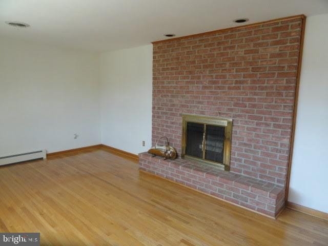 unfurnished living room with a fireplace, wood finished floors, baseboards, and baseboard heating