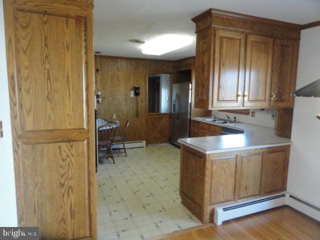 kitchen featuring brown cabinets, light floors, stainless steel fridge, and a baseboard radiator