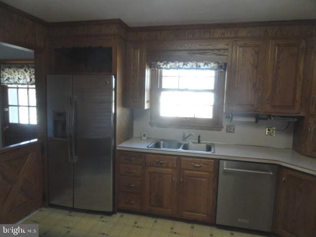 kitchen with plenty of natural light, light floors, appliances with stainless steel finishes, and a sink