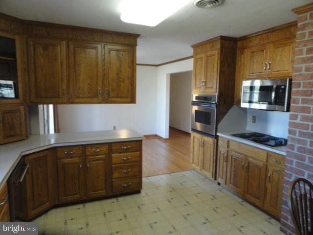 kitchen featuring stainless steel appliances, light floors, and visible vents