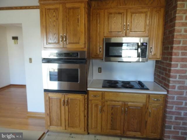 kitchen with light countertops, brown cabinetry, baseboards, and appliances with stainless steel finishes