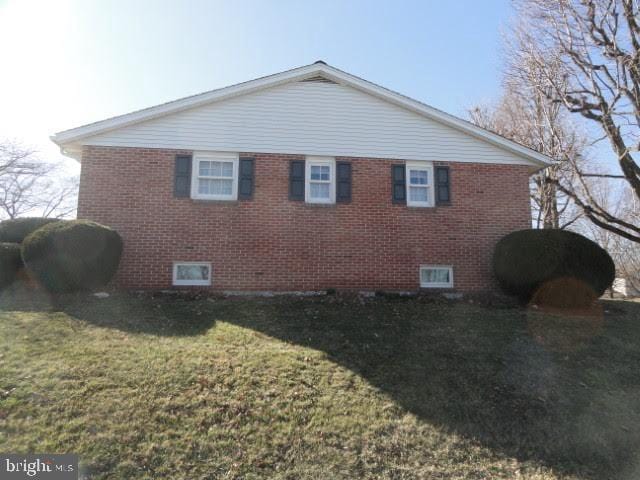 view of home's exterior with brick siding and a lawn