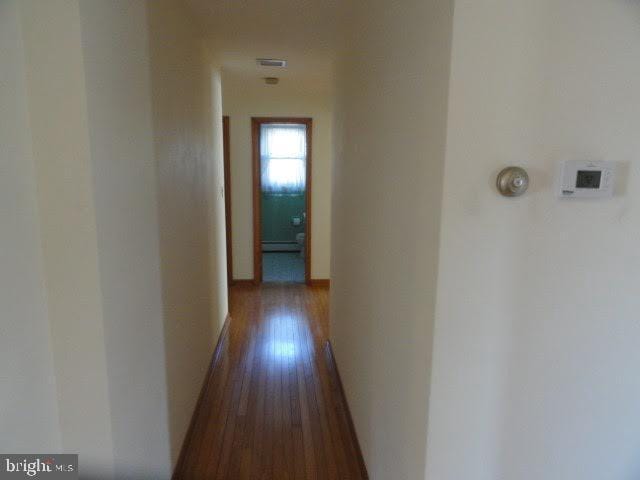 hall with a baseboard heating unit, dark wood-type flooring, and baseboards