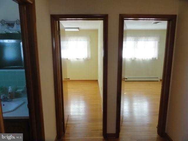 hallway featuring a baseboard heating unit and wood finished floors