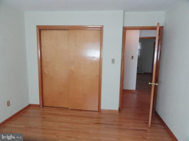 unfurnished bedroom featuring a closet, baseboards, and wood finished floors