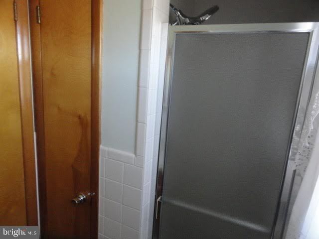 interior details featuring a shower stall and wainscoting