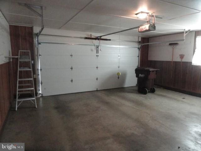 garage featuring a wainscoted wall, wood walls, and a garage door opener