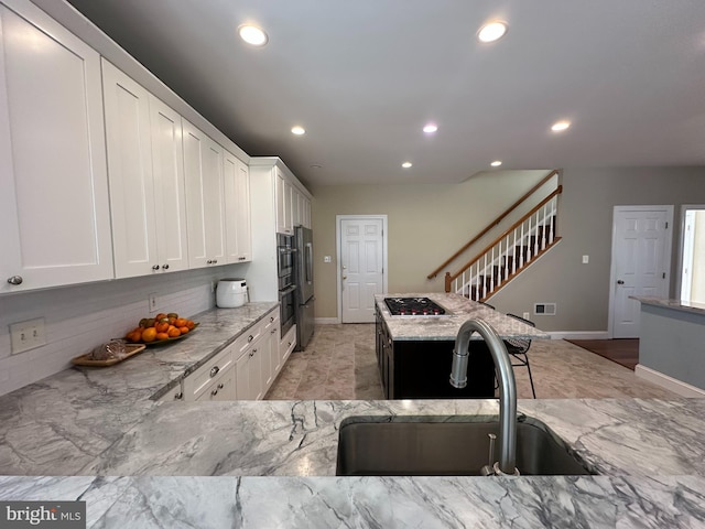 kitchen featuring stainless steel gas stovetop, recessed lighting, light stone counters, and a sink