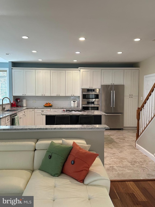 kitchen featuring tasteful backsplash, white cabinets, appliances with stainless steel finishes, and a sink