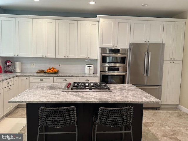 kitchen with a breakfast bar area, a center island, tasteful backsplash, and stainless steel appliances