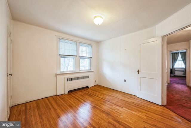 unfurnished room featuring wood finished floors and radiator heating unit
