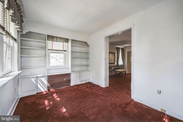 empty room featuring baseboards, ornamental molding, and dark colored carpet