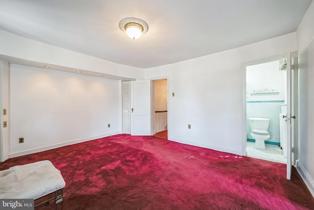 carpeted bedroom featuring baseboards and ensuite bath