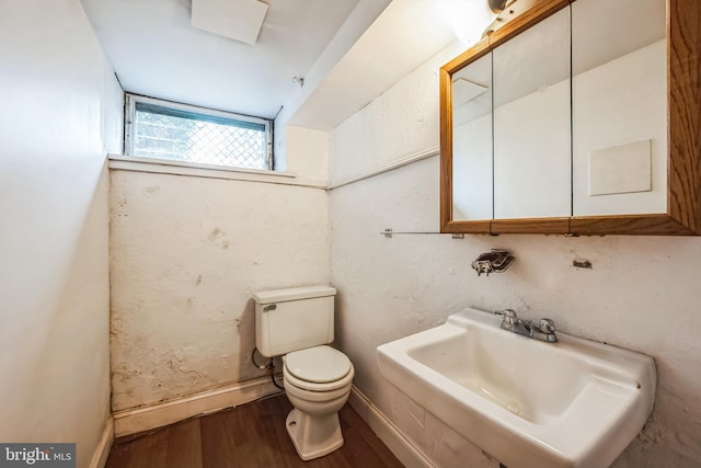 bathroom with toilet, a sink, baseboards, and wood finished floors