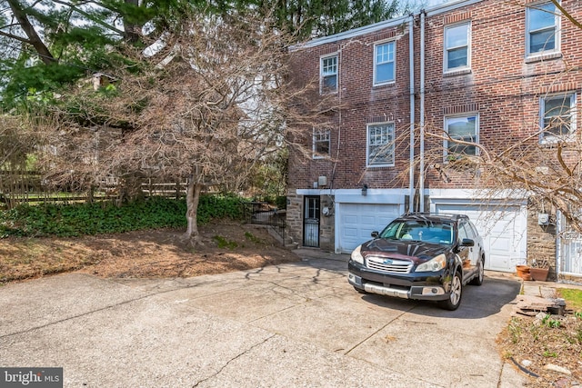 view of front of house featuring driveway, an attached garage, and brick siding