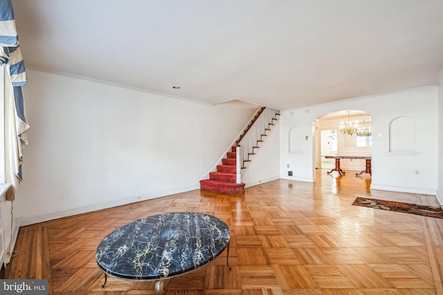 foyer entrance featuring a chandelier, crown molding, baseboards, stairs, and arched walkways