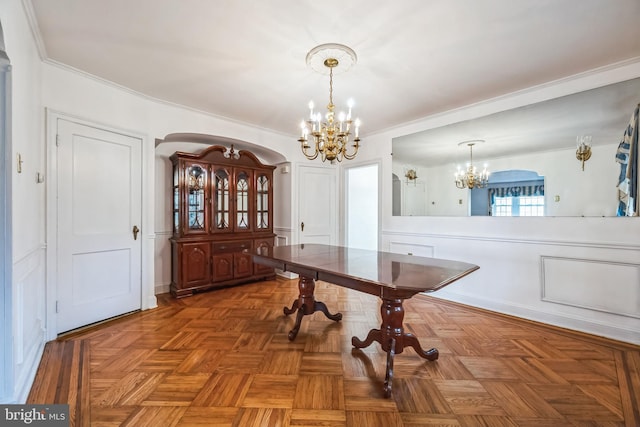 dining space featuring arched walkways, ornamental molding, and a notable chandelier