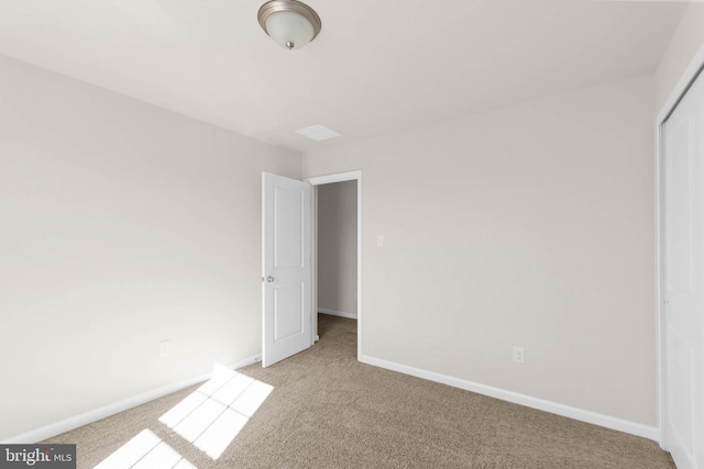 unfurnished bedroom featuring light carpet, a closet, and baseboards