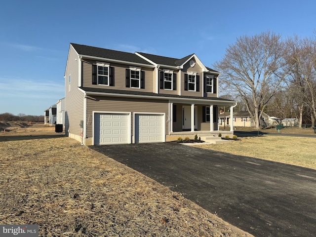 view of front facade with aphalt driveway, a garage, covered porch, and a front yard