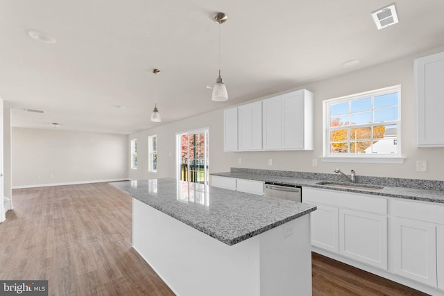 kitchen with visible vents, a center island, stainless steel dishwasher, wood finished floors, and a sink