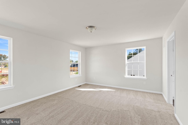 empty room featuring visible vents, baseboards, and carpet floors