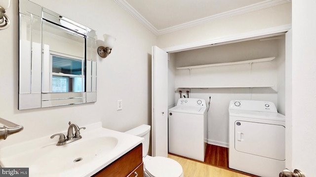 half bath with toilet, ornamental molding, wood finished floors, independent washer and dryer, and vanity