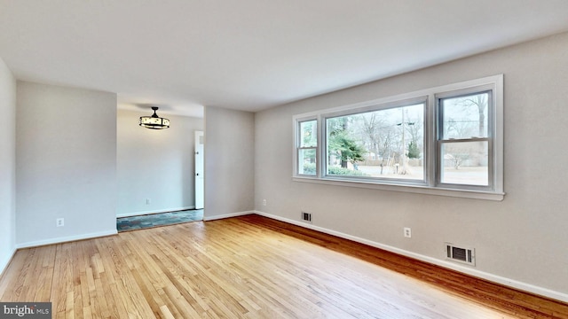 unfurnished room featuring visible vents, baseboards, and wood finished floors